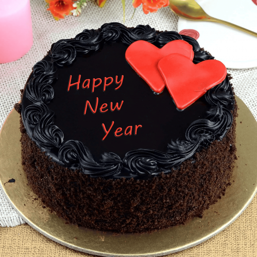 A chocolate cake with black icing and red heart-shaped decorations, with "Happy New Year" written on top.