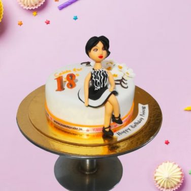A cake with a figurine of a girl celebrating an 18th birthday
