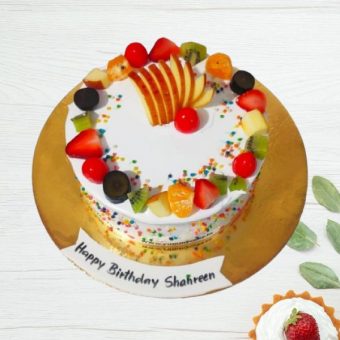 Fruit-topped birthday cake with "Happy Birthday Shahreen" on it