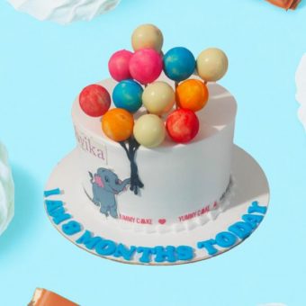 A cake with an elephant and colorful balloons