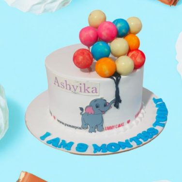 A cake with an elephant and colorful balloons celebrating a baby's 8-month milestone