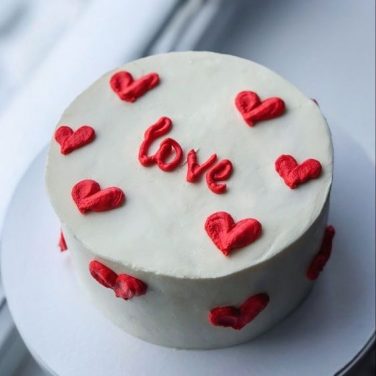 White cake with red "love" and heart decorations on top