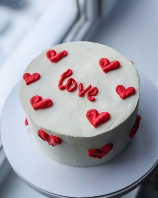 White cake with red "love" and heart decorations on top