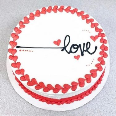White cake with red heart border and "love" written in the center