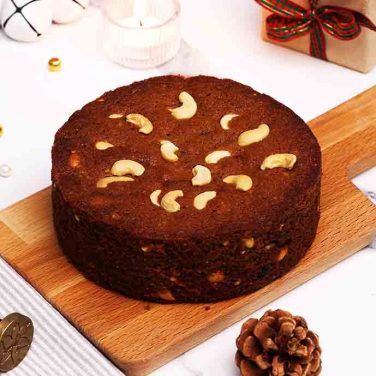 plum cake with cashew nuts on a wooden board