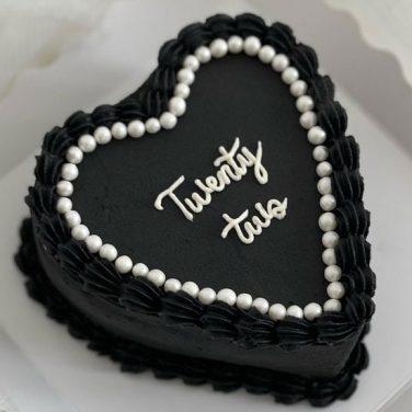 A heart shape black in color premium cake with a twenty two written on the cake