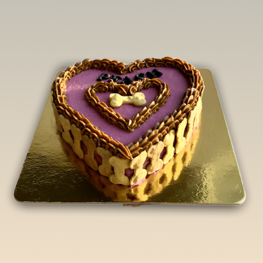 Heart-shaped dog birthday cake with pink frosting, bone-shaped treats, and decorative heart icing
