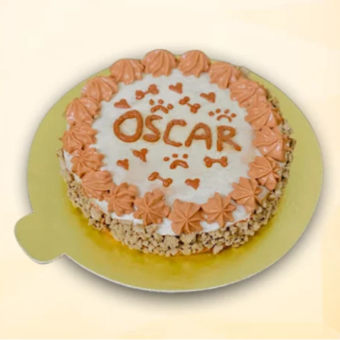 Round dog cake with the name “Oscar” in orange frosting, paw prints, hearts